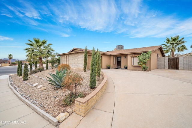 ranch-style house with fence, concrete driveway, and brick siding