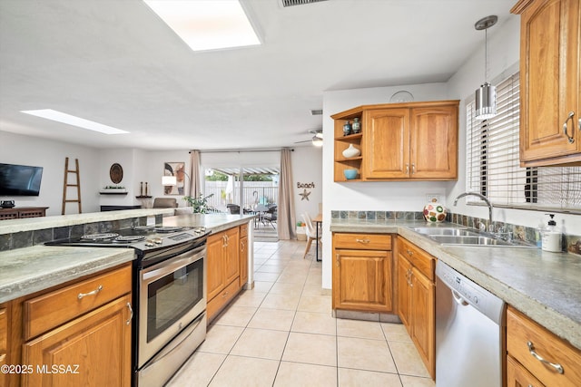 kitchen featuring a skylight, stainless steel appliances, brown cabinetry, light tile patterned flooring, and a sink