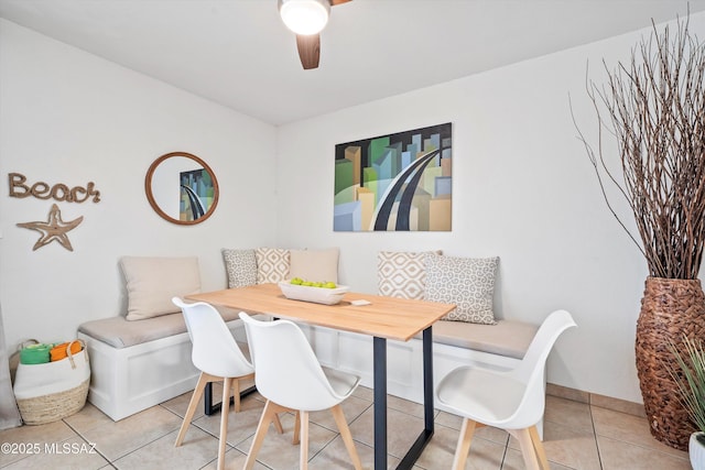 dining space with light tile patterned floors, baseboards, breakfast area, and a ceiling fan