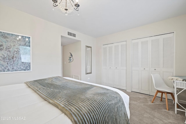 bedroom with multiple closets, a chandelier, visible vents, and carpet flooring