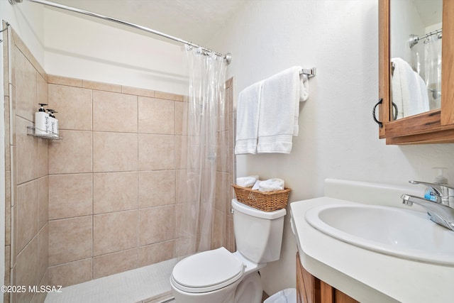 bathroom featuring tiled shower, vanity, and toilet