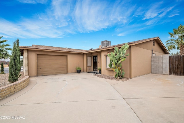 view of front of home featuring driveway, an attached garage, cooling unit, and fence