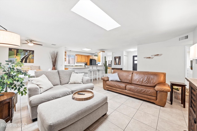 living room with a skylight, a healthy amount of sunlight, visible vents, and light tile patterned floors