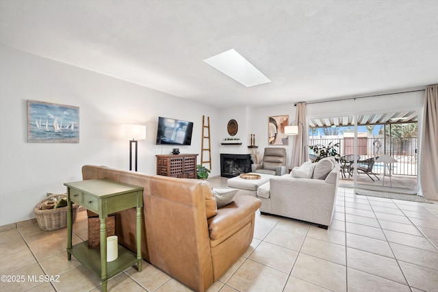 living room with a skylight, a fireplace, and light tile patterned floors