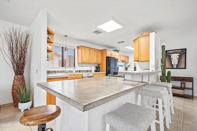 kitchen with a peninsula, visible vents, a kitchen breakfast bar, light countertops, and freestanding refrigerator