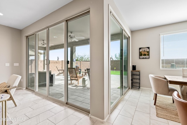 doorway with a healthy amount of sunlight, ceiling fan, and baseboards