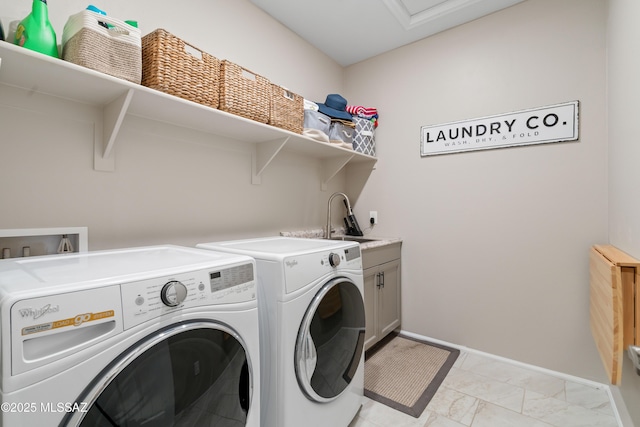 washroom with a sink, baseboards, marble finish floor, cabinet space, and washer and clothes dryer