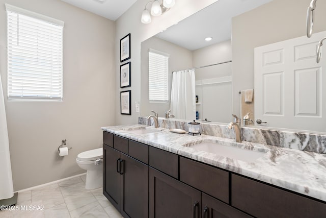 bathroom with toilet, marble finish floor, a wealth of natural light, and a sink