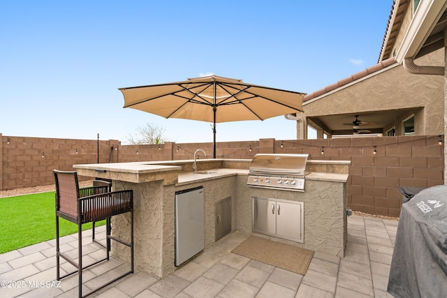 view of patio / terrace featuring a fenced backyard, a sink, grilling area, and an outdoor kitchen