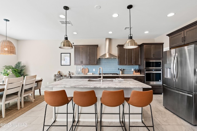 kitchen with stainless steel appliances, dark brown cabinets, wall chimney exhaust hood, and visible vents