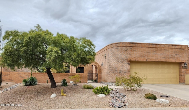 view of front of house with brick siding, an attached garage, driveway, and fence