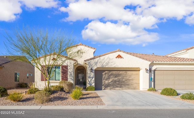 mediterranean / spanish home with a garage, driveway, a tiled roof, and stucco siding