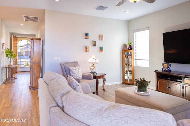 living area featuring light wood-type flooring, visible vents, and baseboards