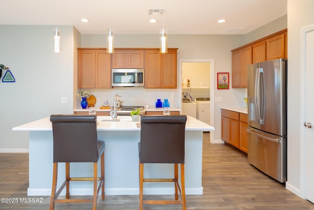 kitchen featuring tasteful backsplash, light countertops, visible vents, appliances with stainless steel finishes, and washing machine and dryer