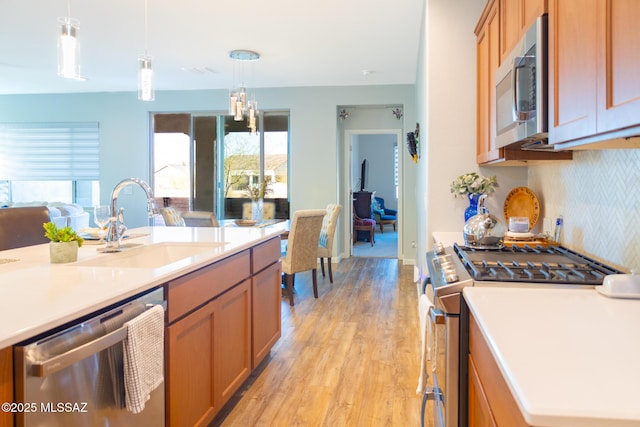 kitchen featuring light wood-style flooring, stainless steel appliances, a sink, a wealth of natural light, and decorative backsplash