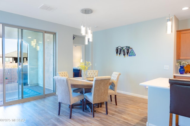 dining space featuring light wood-style floors, baseboards, and visible vents