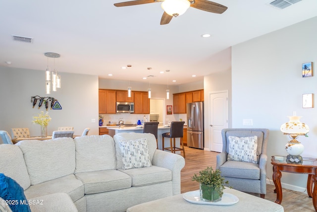 living area with recessed lighting, visible vents, and light wood-style flooring