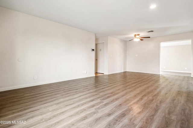 spare room featuring baseboards, wood finished floors, visible vents, and a ceiling fan