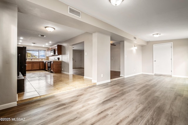 unfurnished living room featuring light wood-style flooring, visible vents, and baseboards