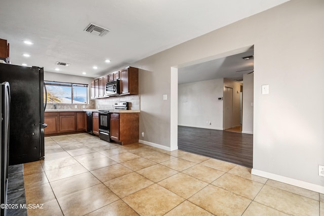 kitchen with light tile patterned floors, visible vents, decorative backsplash, light countertops, and black appliances