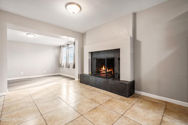 unfurnished living room with a fireplace, baseboards, and light tile patterned floors