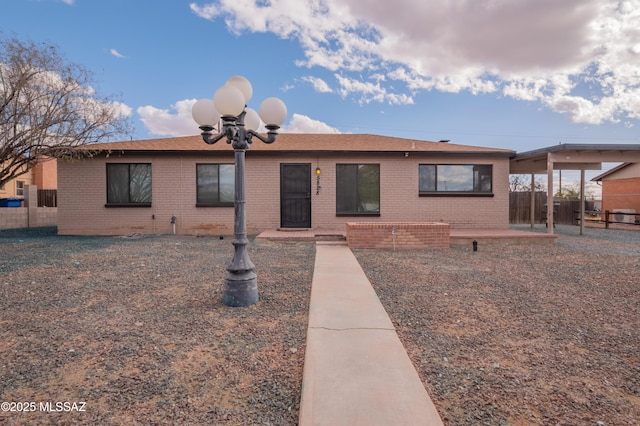 single story home featuring brick siding, fence, and a patio