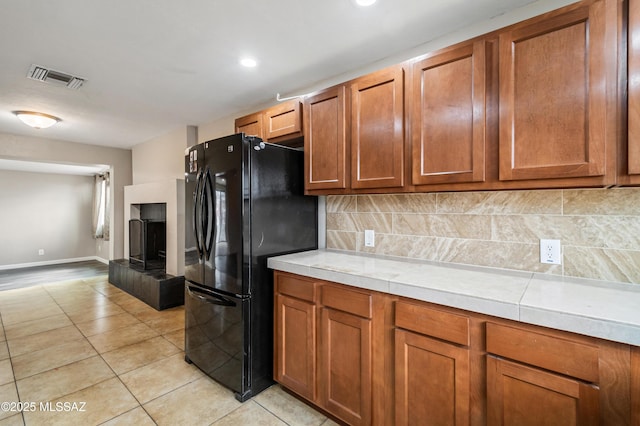 kitchen with brown cabinetry, freestanding refrigerator, and visible vents