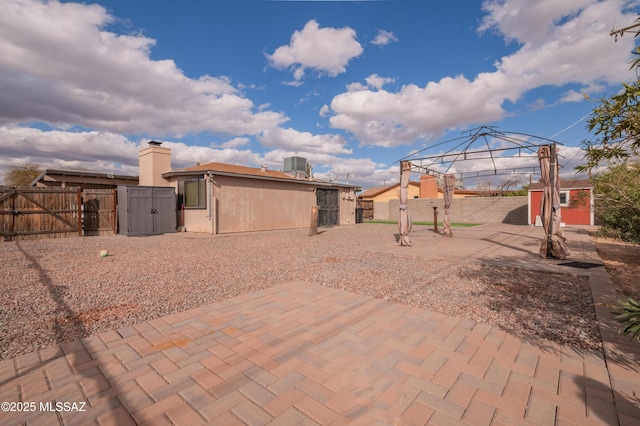 view of patio with an outbuilding, a gazebo, a gate, fence, and cooling unit