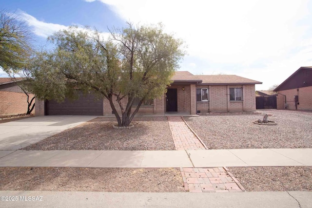 single story home with a garage, driveway, brick siding, and fence