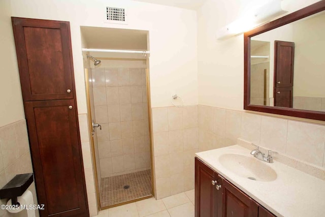 bathroom with tile walls, visible vents, wainscoting, a shower stall, and vanity