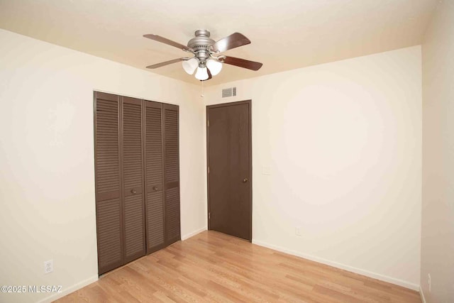 unfurnished bedroom with baseboards, visible vents, a ceiling fan, wood finished floors, and a closet