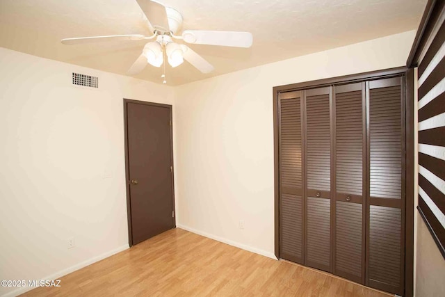 unfurnished bedroom with a closet, visible vents, a ceiling fan, light wood-type flooring, and baseboards