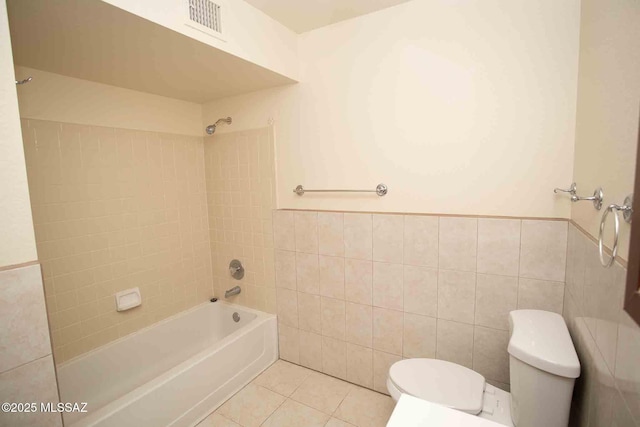 full bath with tile walls, toilet, wainscoting, tub / shower combination, and tile patterned floors