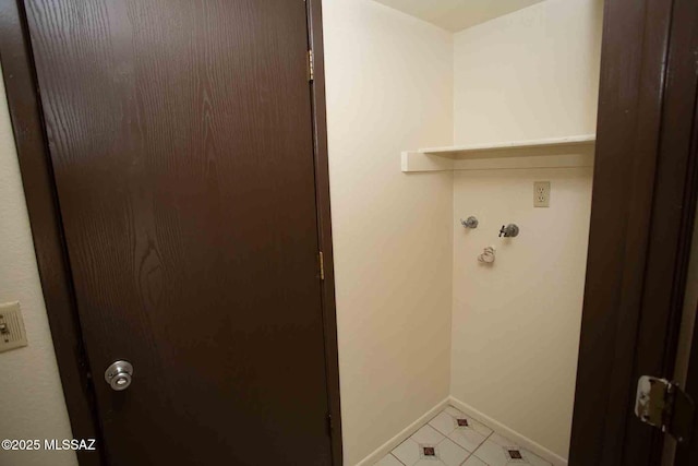 laundry area featuring laundry area, baseboards, and light tile patterned floors