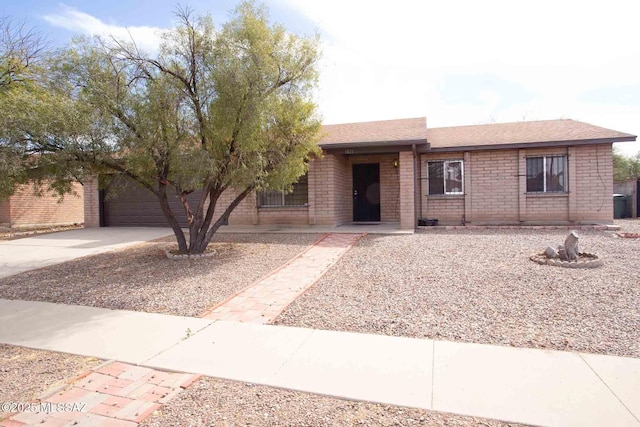 ranch-style home with a garage, concrete driveway, brick siding, and a shingled roof