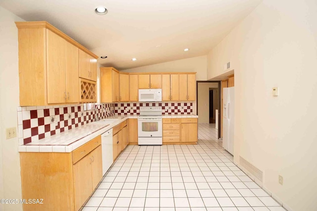 kitchen featuring tile countertops, light brown cabinets, white appliances, vaulted ceiling, and decorative backsplash