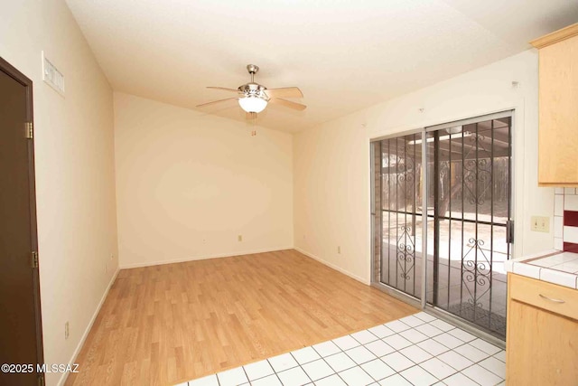 unfurnished room featuring baseboards, a ceiling fan, visible vents, and light wood-style floors