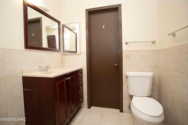 bathroom featuring toilet, vanity, tile walls, and tile patterned floors