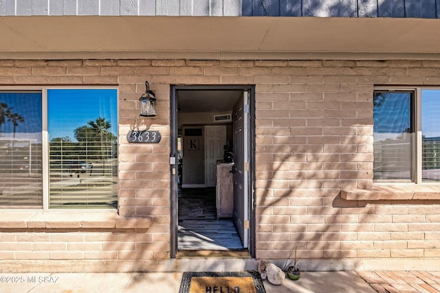 entrance to property featuring visible vents and brick siding