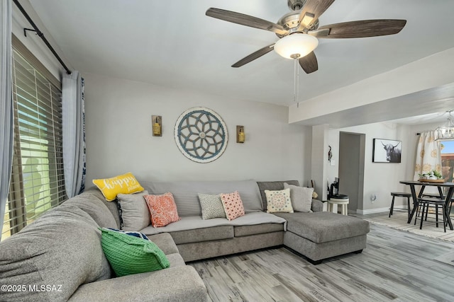 living area with baseboards, a ceiling fan, and light wood-style floors