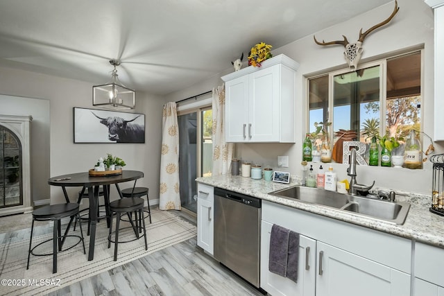 kitchen featuring a sink, baseboards, light wood-style floors, white cabinets, and stainless steel dishwasher