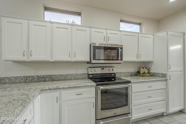 kitchen with light tile patterned flooring, recessed lighting, white cabinetry, appliances with stainless steel finishes, and light stone countertops