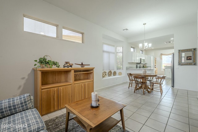 living room featuring light tile patterned floors, baseboards, visible vents, and a notable chandelier