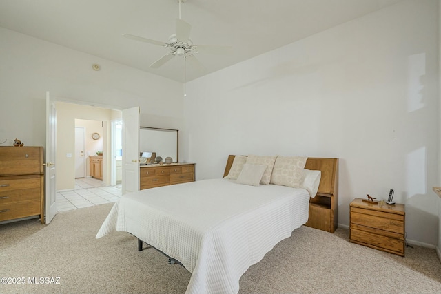 bedroom with a ceiling fan, light colored carpet, ensuite bath, and light tile patterned floors