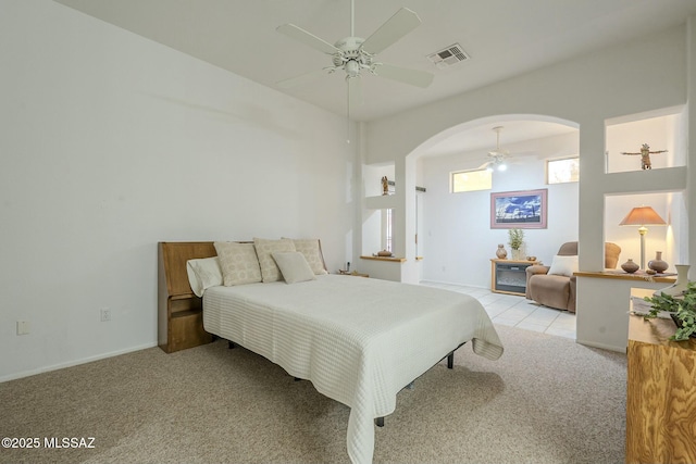 bedroom with carpet floors, visible vents, arched walkways, and a ceiling fan