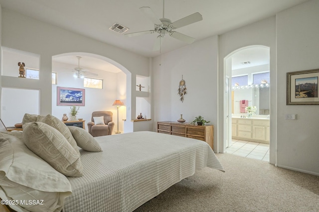 bedroom featuring a ceiling fan, visible vents, light carpet, and ensuite bath