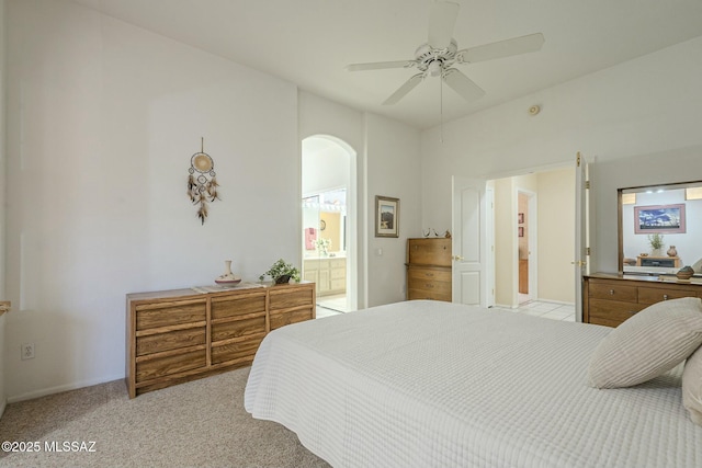 bedroom featuring arched walkways, light colored carpet, ceiling fan, and ensuite bathroom