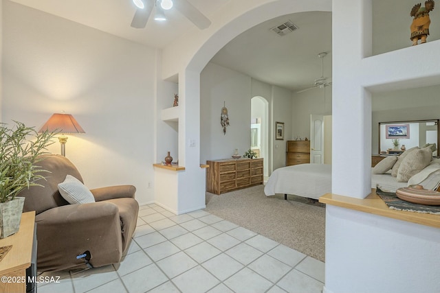 bedroom featuring arched walkways, light tile patterned flooring, light carpet, visible vents, and a ceiling fan