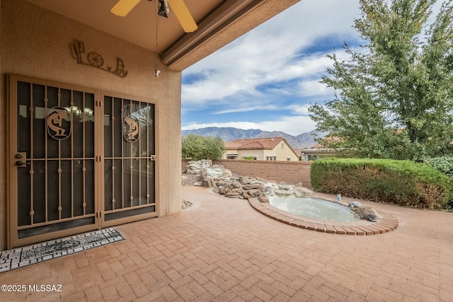 view of patio with ceiling fan, fence, and a mountain view