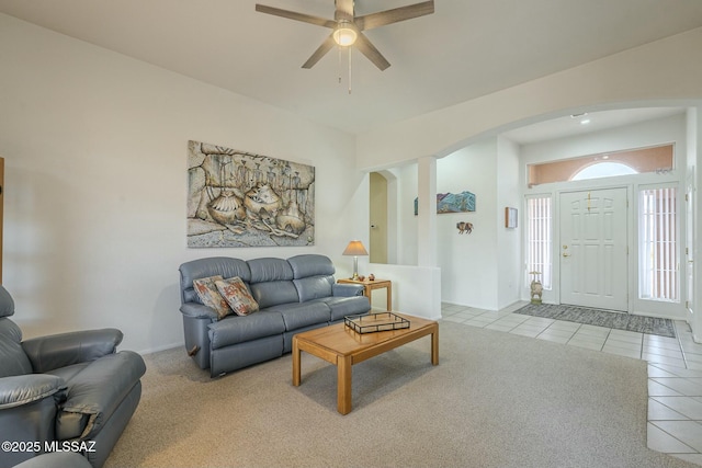 tiled living room featuring a ceiling fan, arched walkways, and baseboards